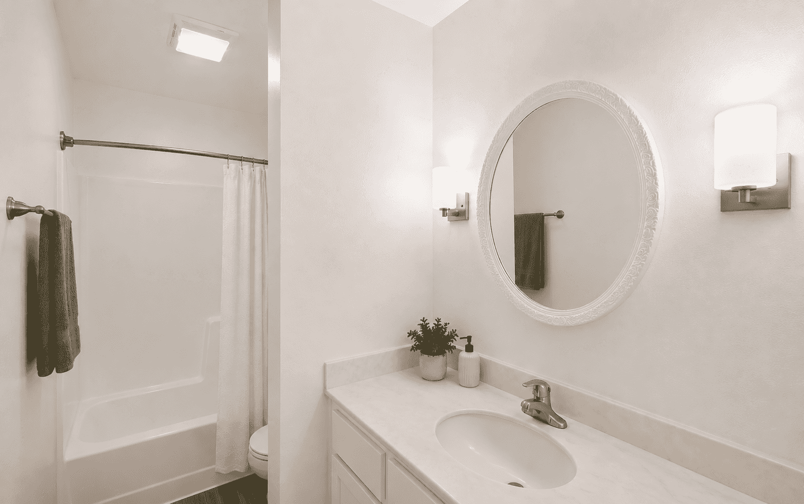 Renovated bathroom with oval mirror and brushed nickel fixtures